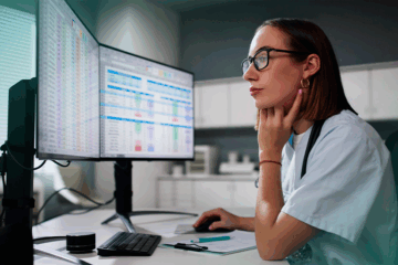 Profissional de saúde utilizando software de gestão de escalas médicas em computador.